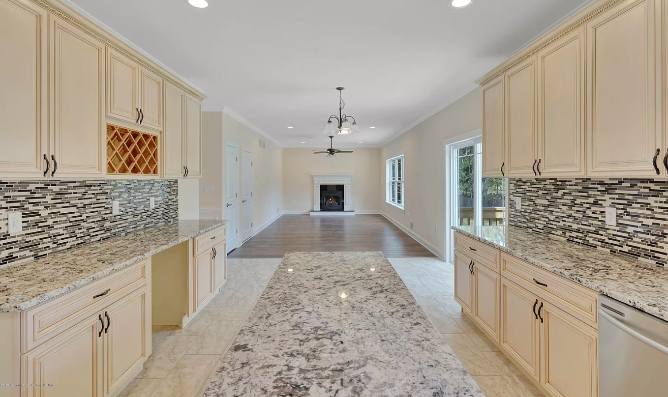 A kitchen in a new home with granite counter tops and white cabinets.