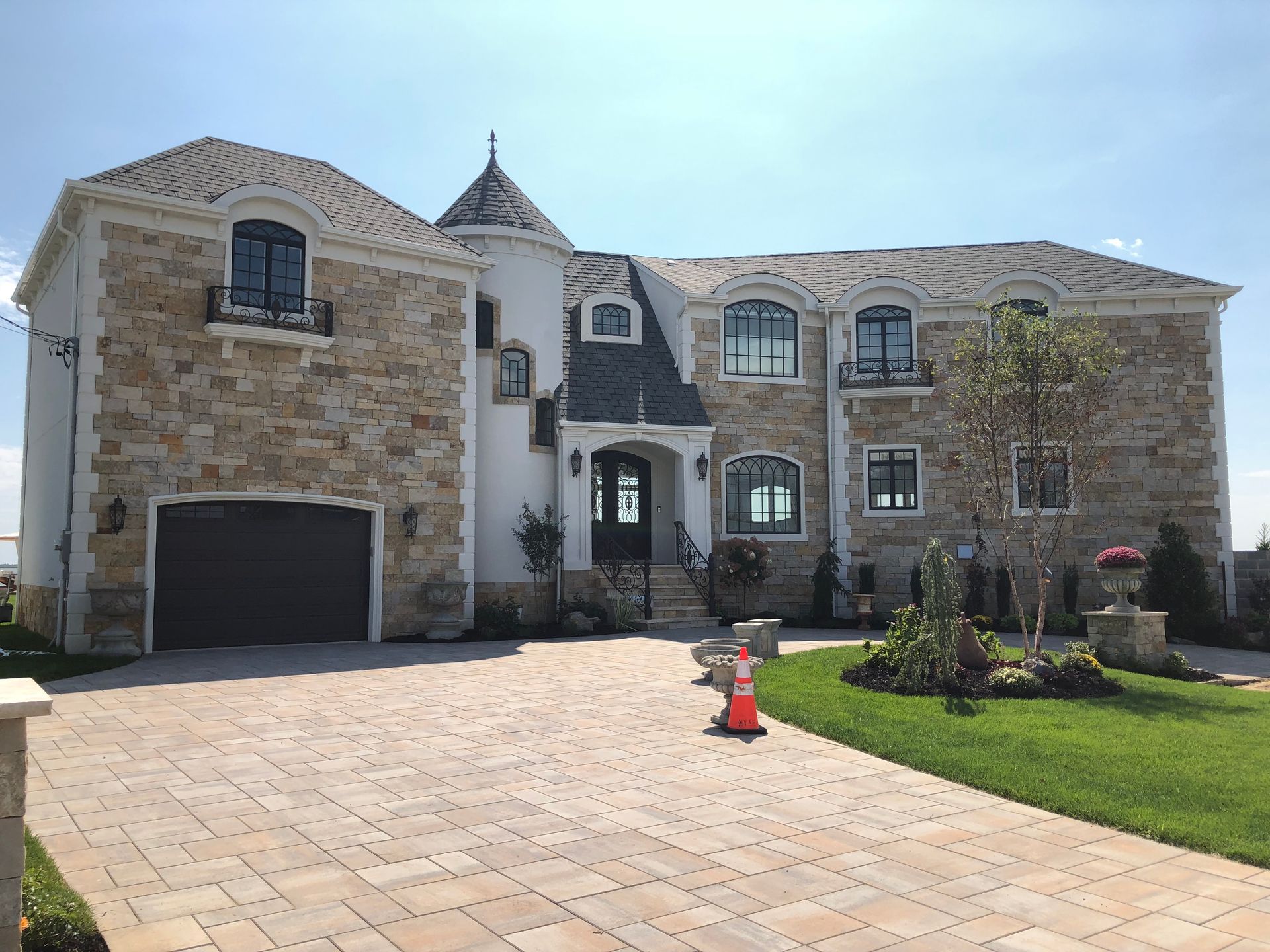 A large house with a brick driveway and a large garage.