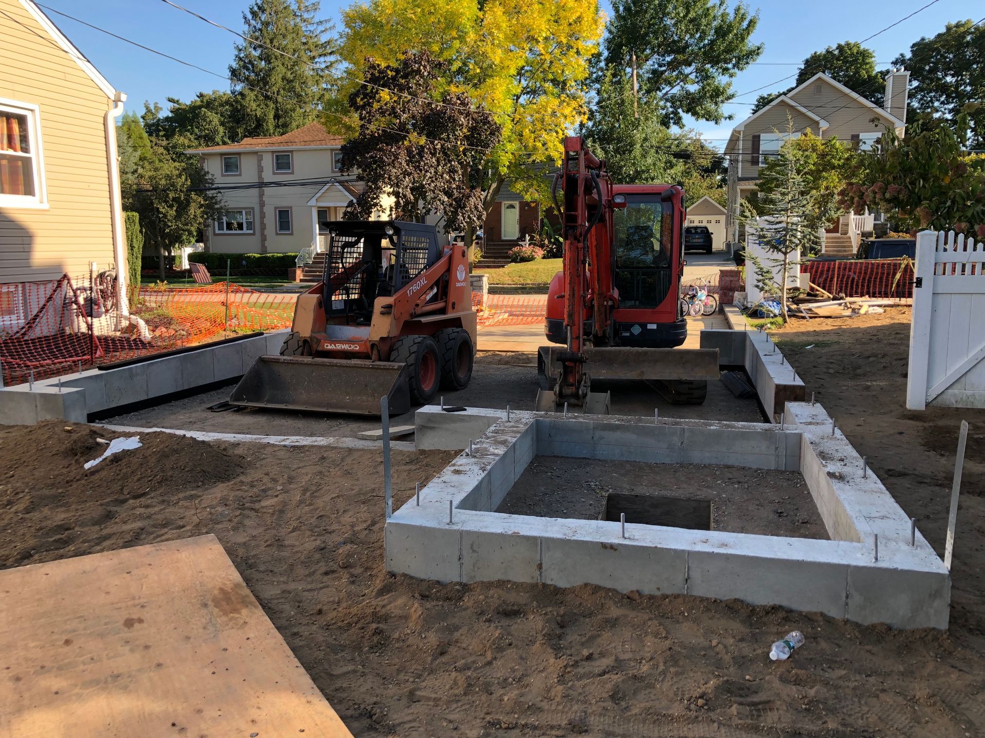 A couple of tractors are parked in front of a house.