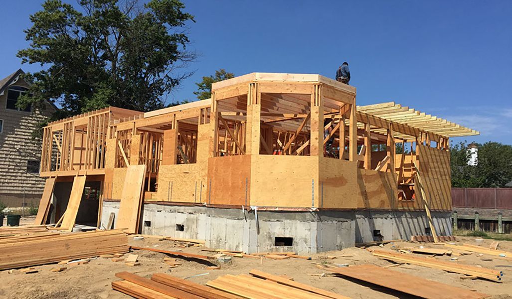 A large wooden house is being built in a construction site.