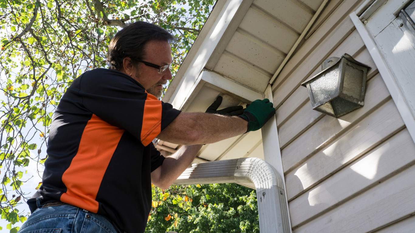A man is working on the side of a house.