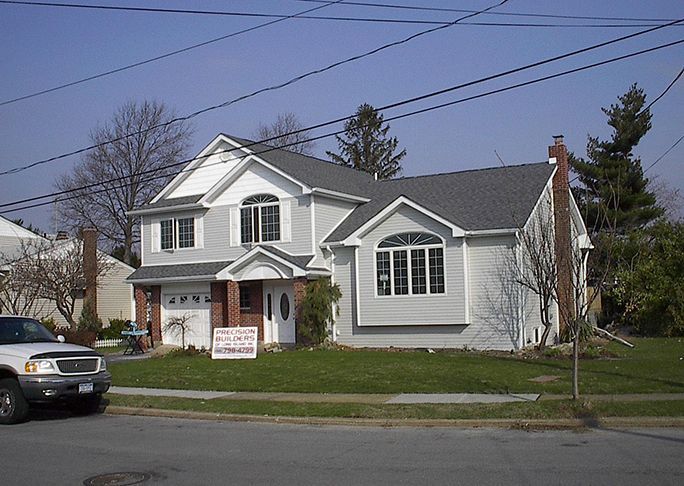 A white truck is parked in front of a white house