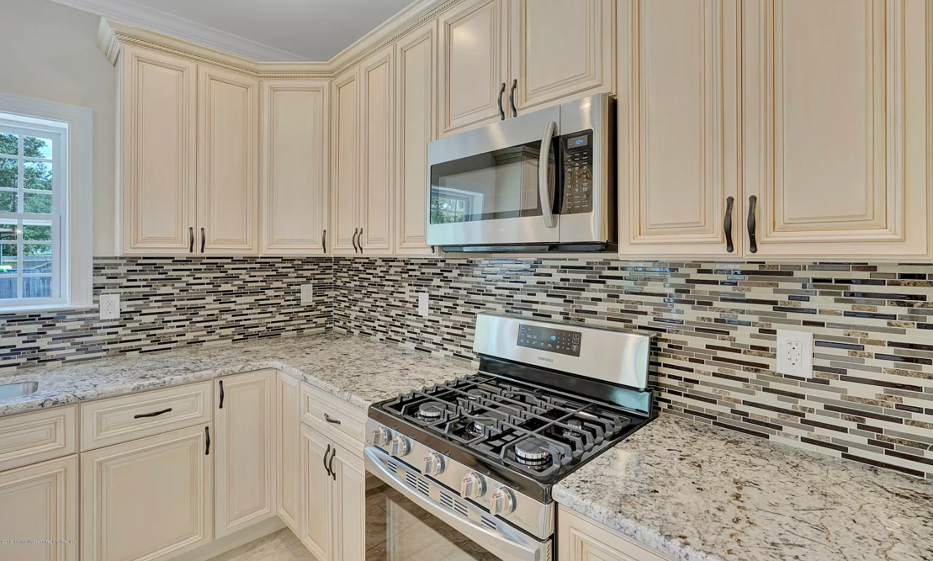 A kitchen with granite counter tops , stainless steel appliances , and white cabinets.