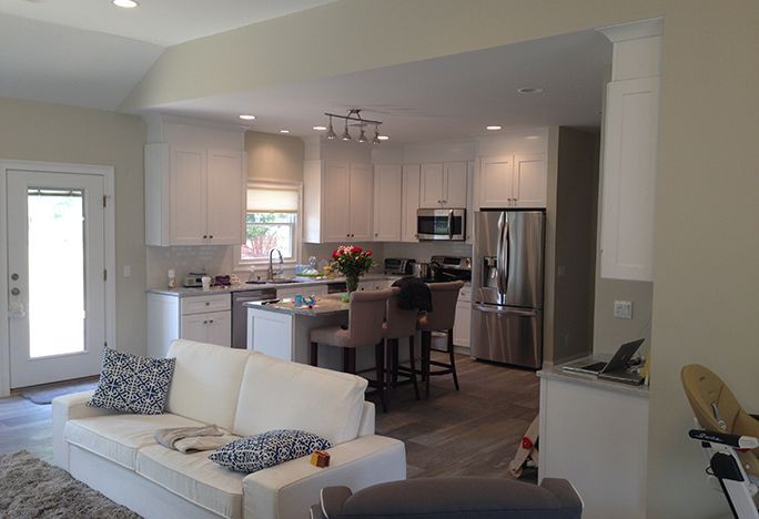 A living room with a white couch and a kitchen with stainless steel appliances
