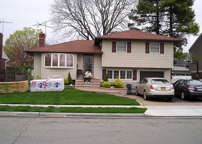 A man sits on the porch of a house that is for sale