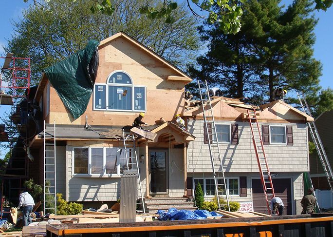 A house is being remodeled with a green tarp on the roof
