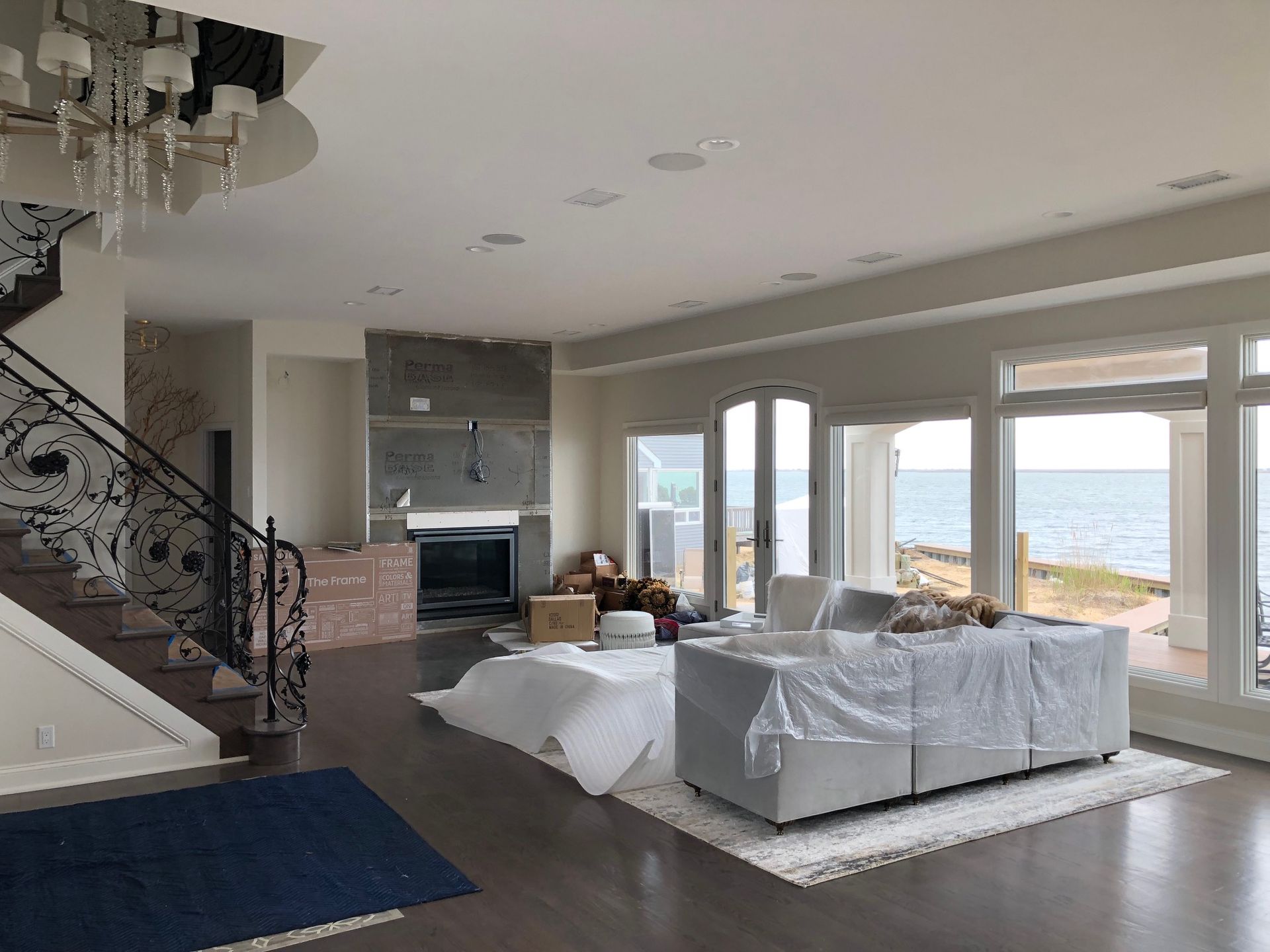 A living room with a couch , fireplace , stairs and a view of the ocean.