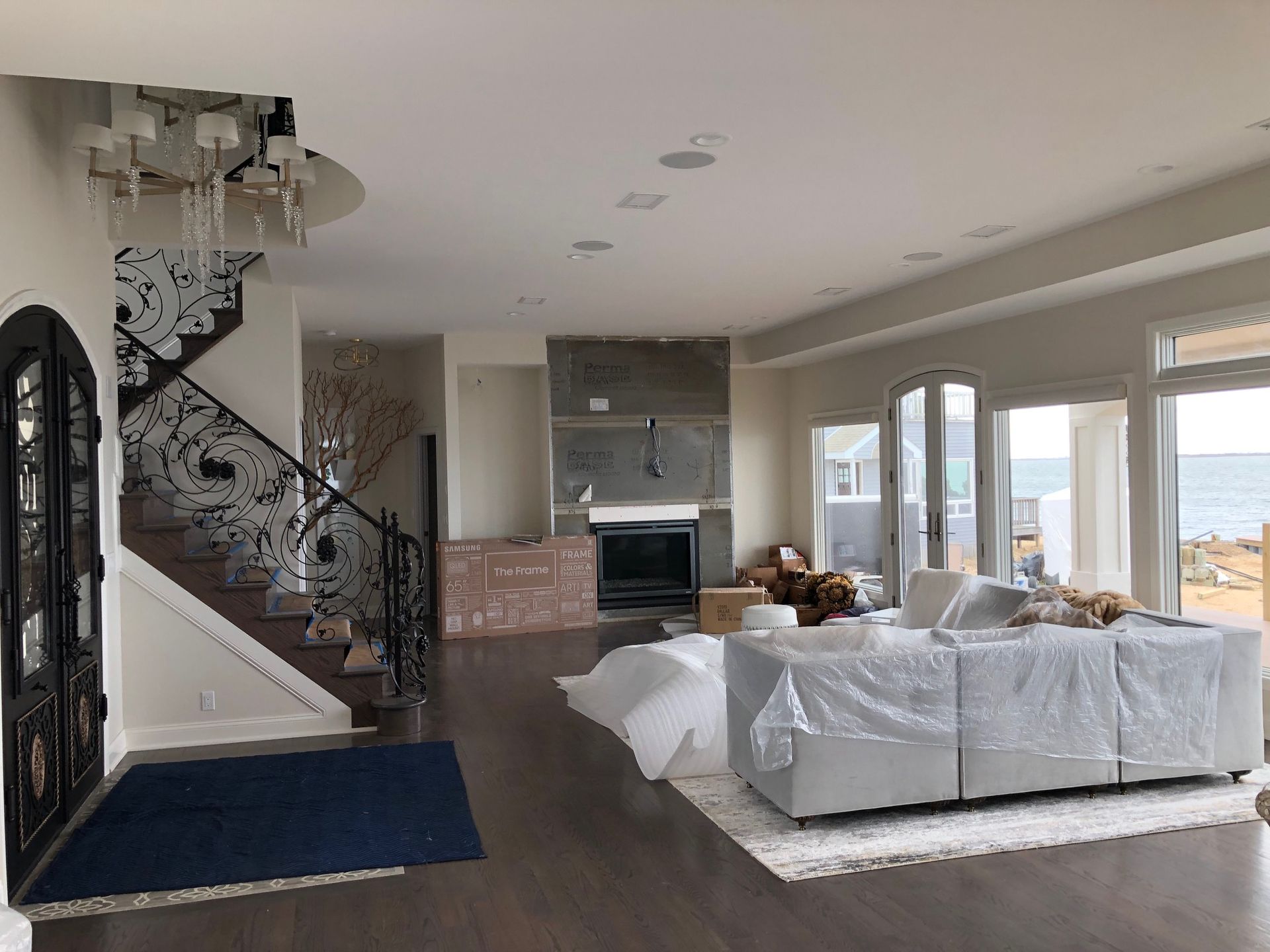A living room with a couch , fireplace , stairs and a view of the ocean.