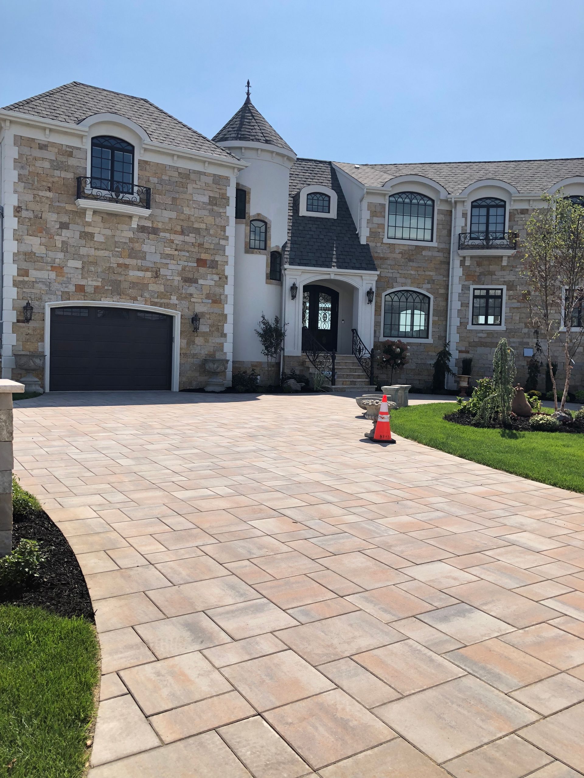 A large stone house with a brick driveway in front of it.