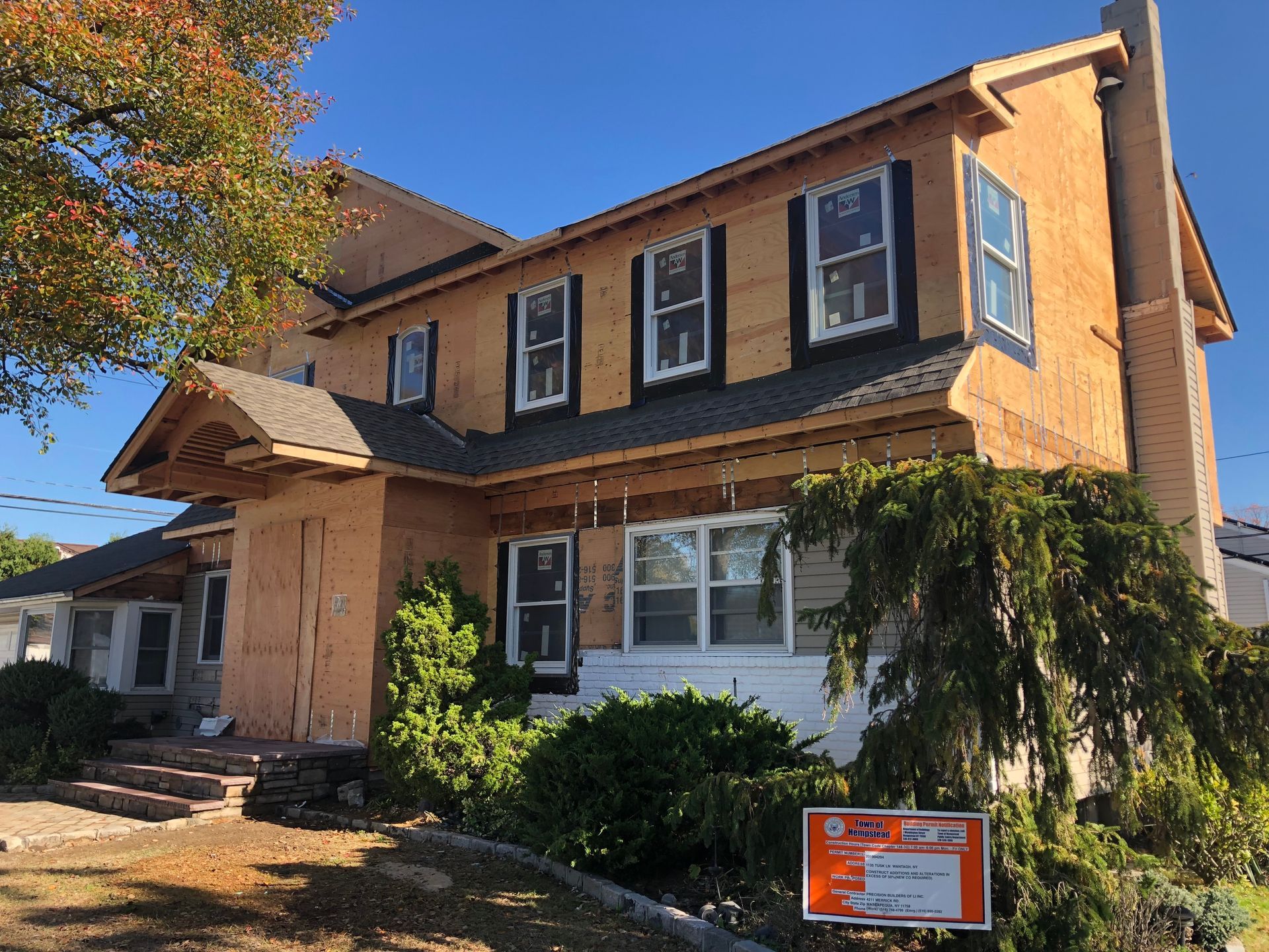 A large house is being built with a sign in front of it.