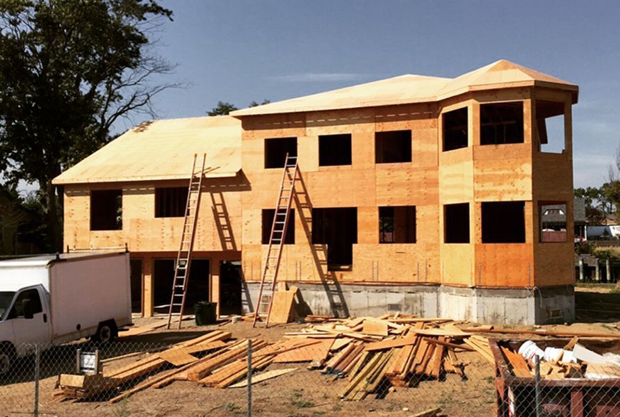 A large wooden house is being built with a lot of windows