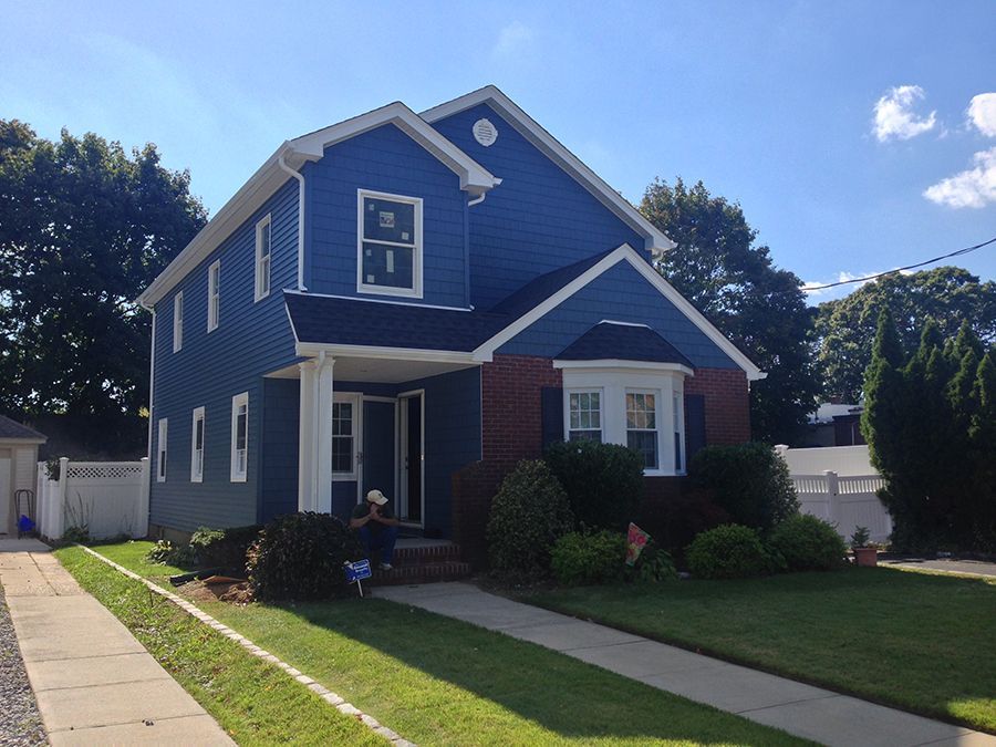A blue house with a white trim and a white fence
