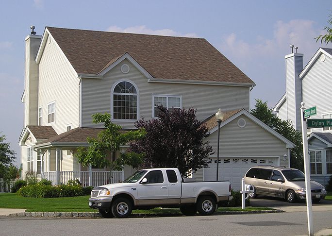 A white truck is parked in front of a house