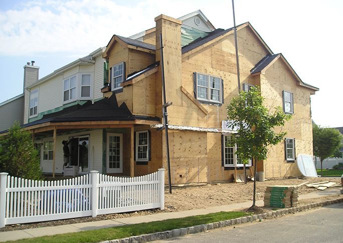 A house under construction with a white picket fence