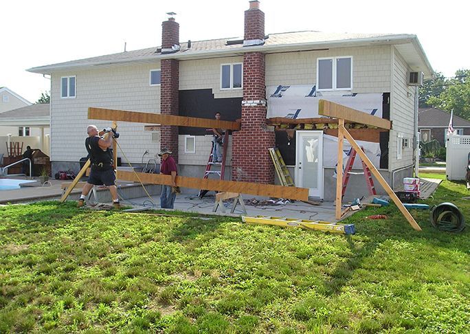 A group of people are working on a house in the backyard.