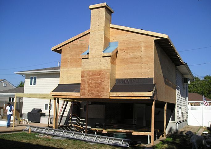 A house is being remodeled with plywood and a chimney