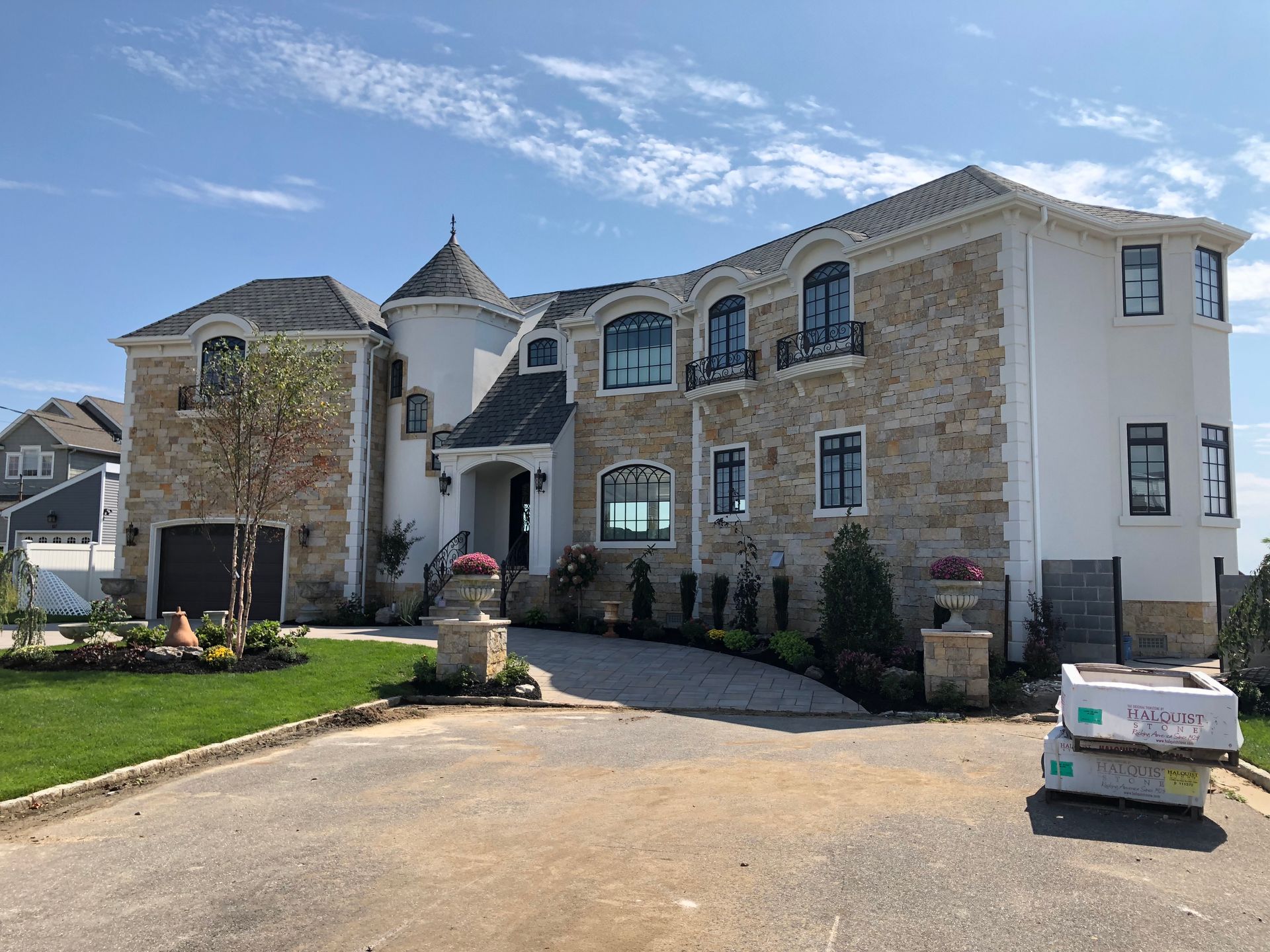A large white house with a stone facade is sitting on top of a lush green hillside.