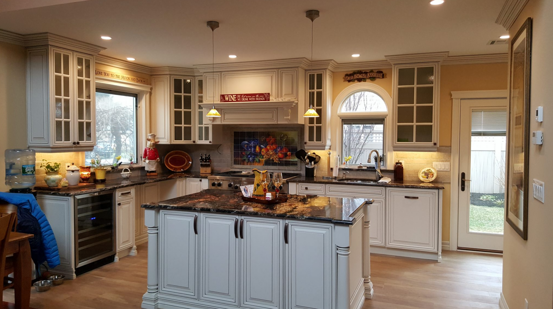 A kitchen with white cabinets , granite counter tops , and a large island.