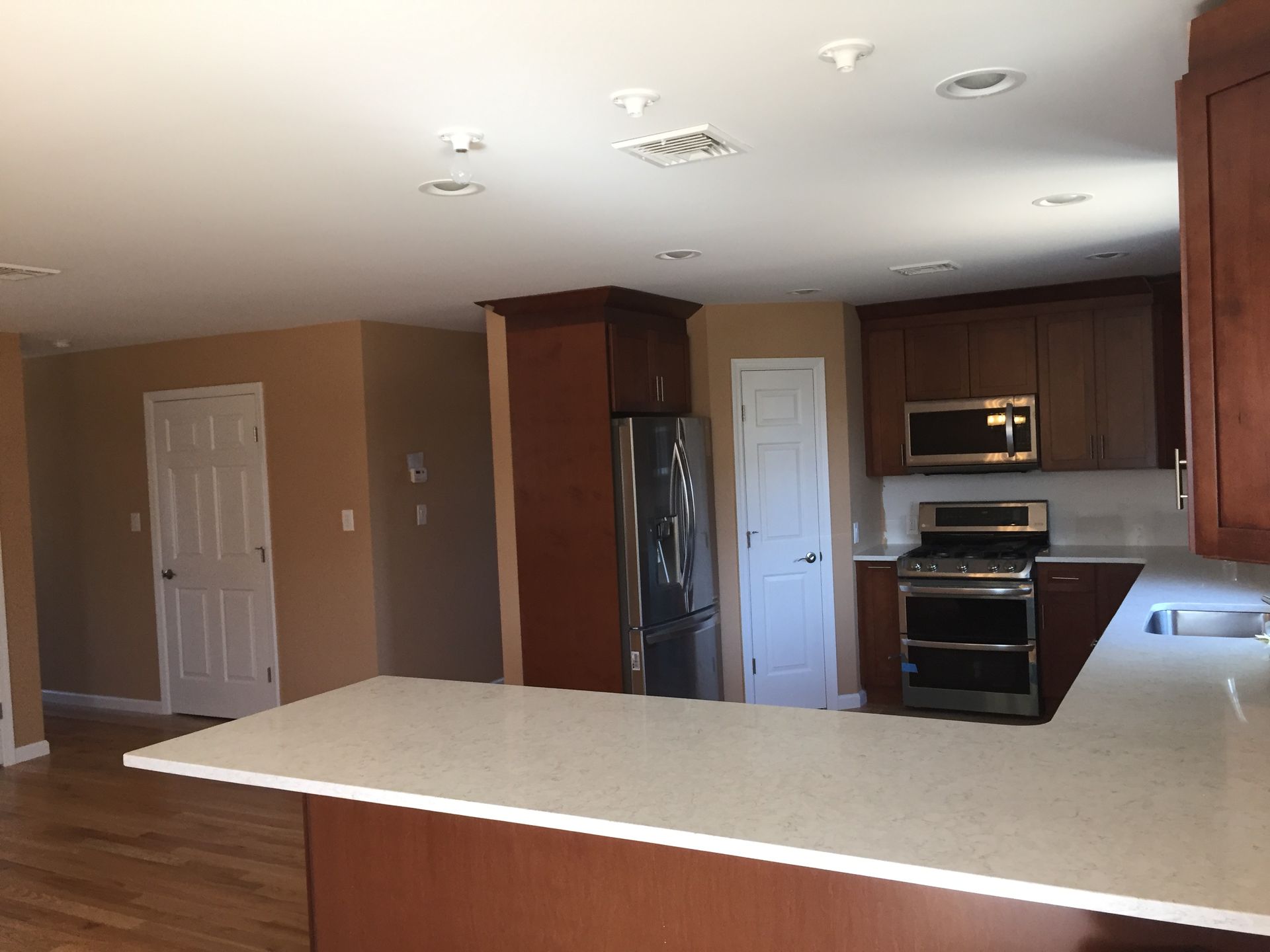 An empty kitchen with a stove , refrigerator and microwave