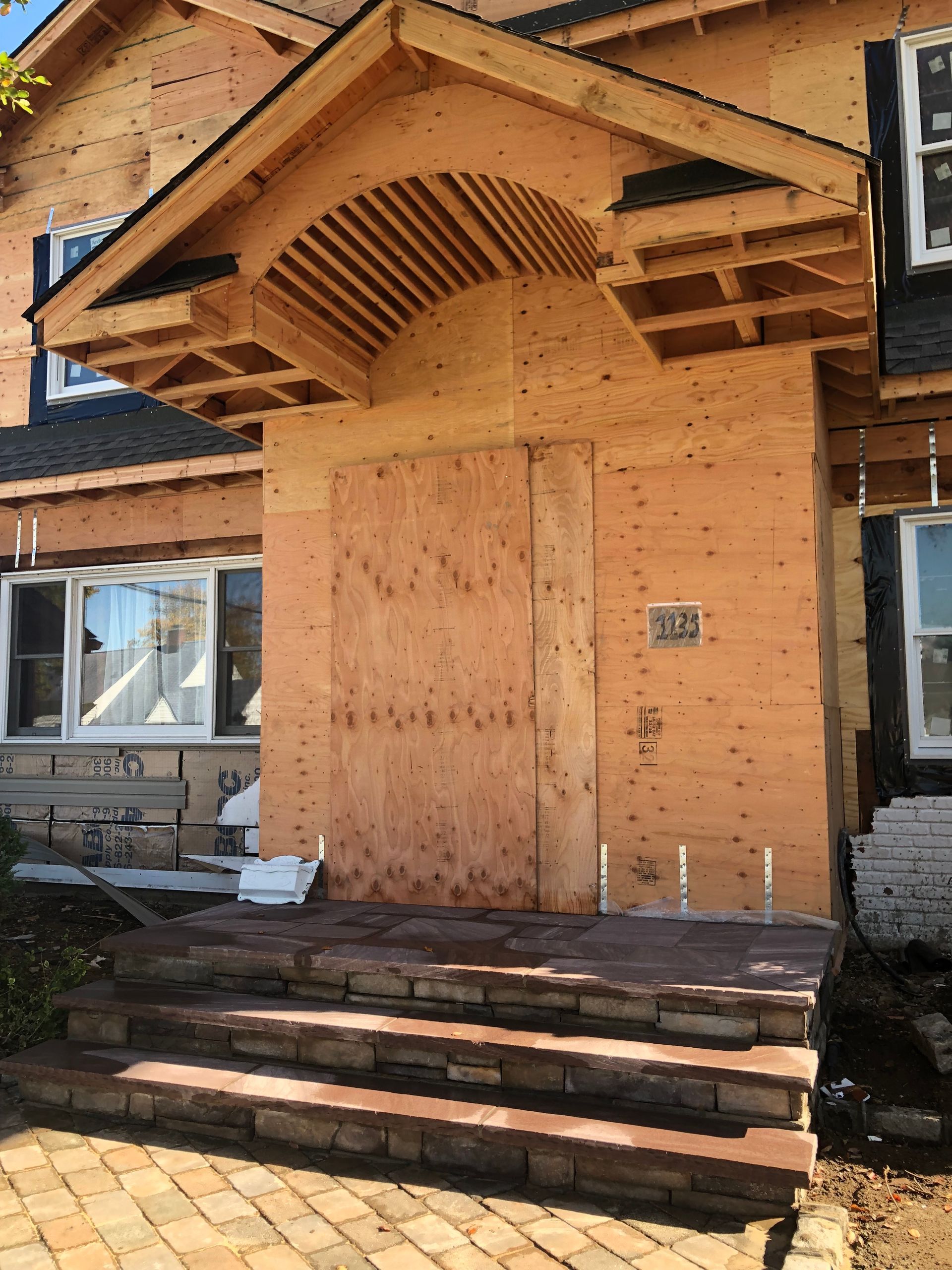 The front door of a house is boarded up with plywood