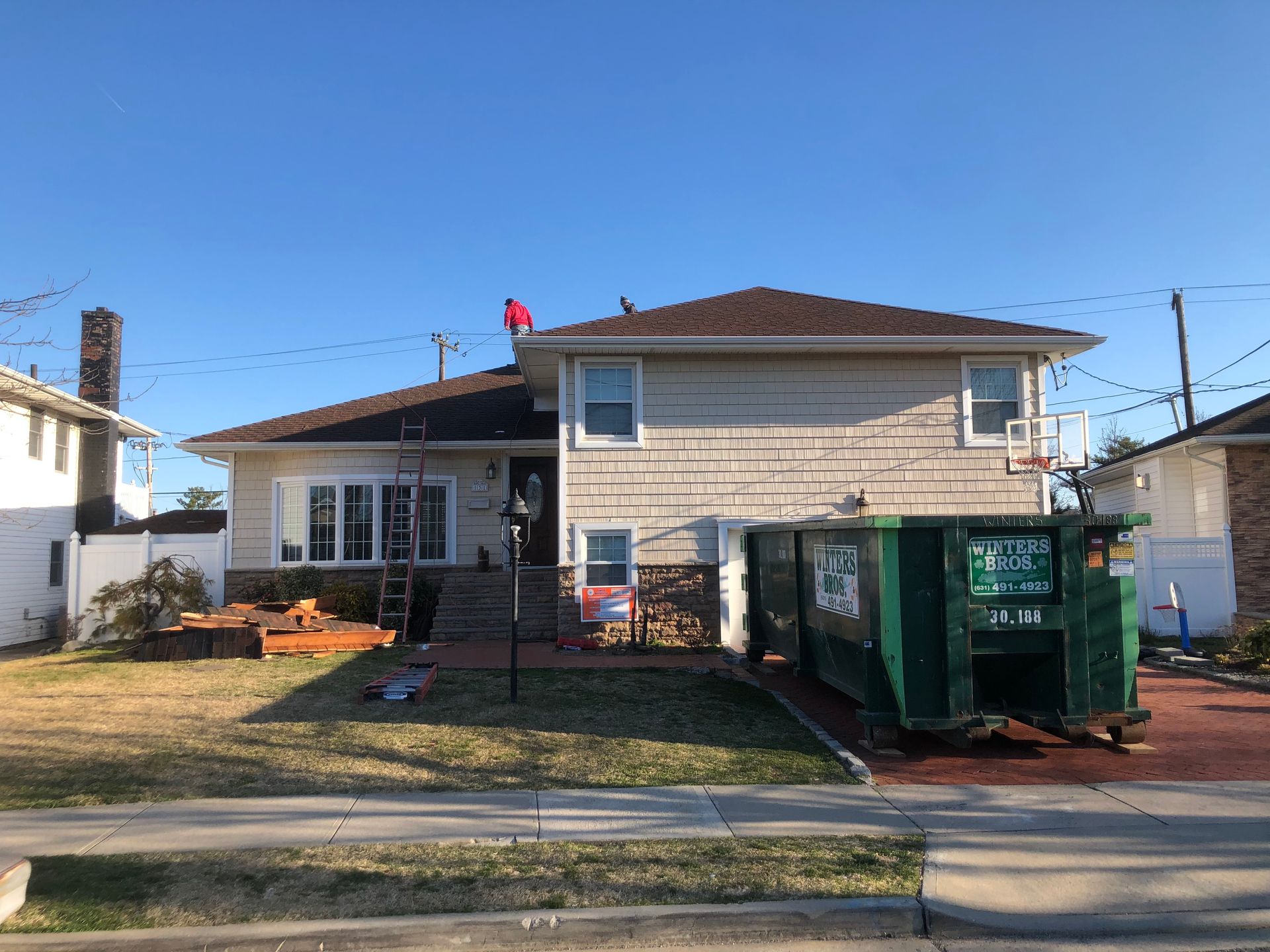 A house with a green dumpster in front of it.