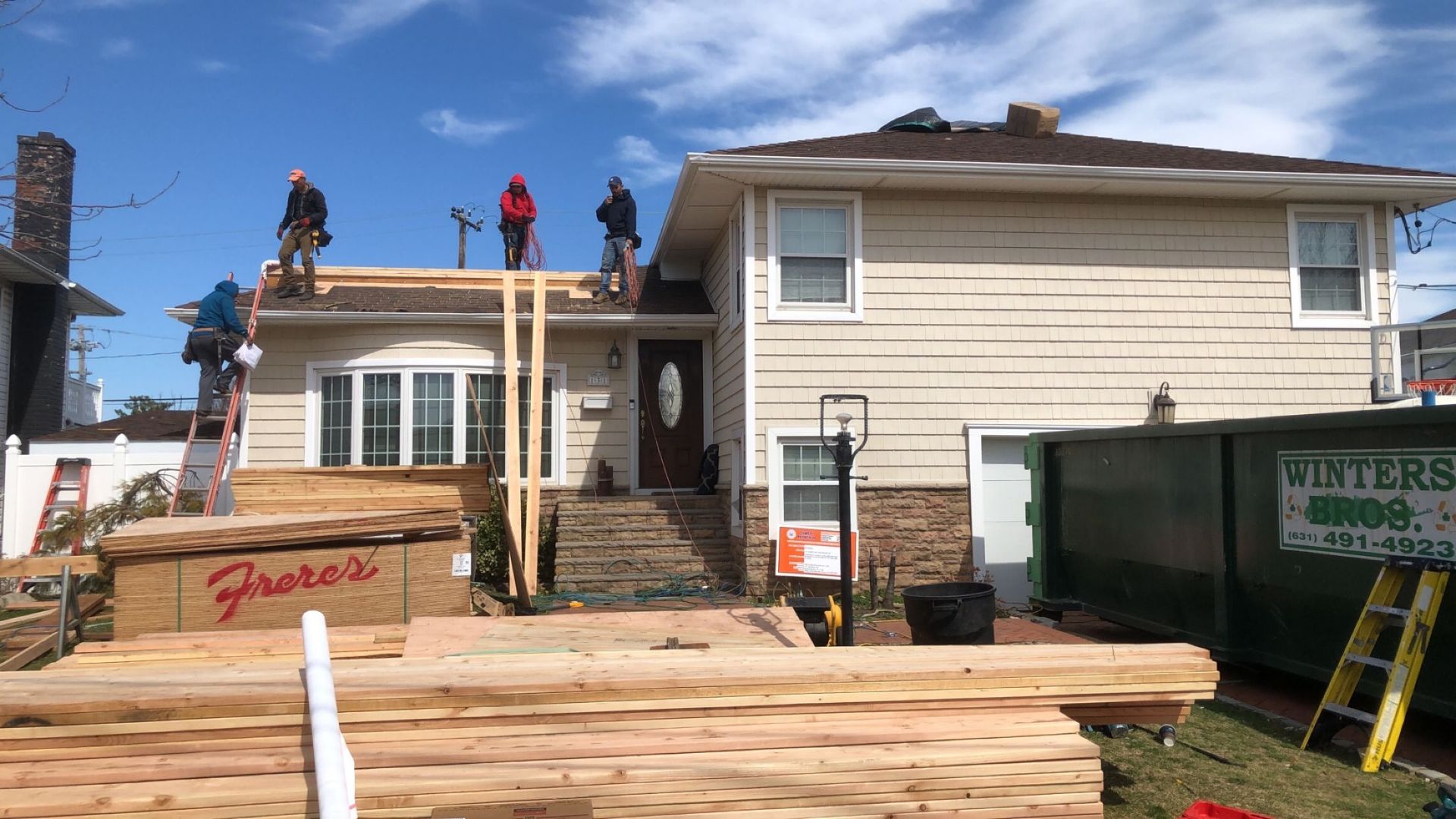 A group of construction workers are working on the roof of a house.