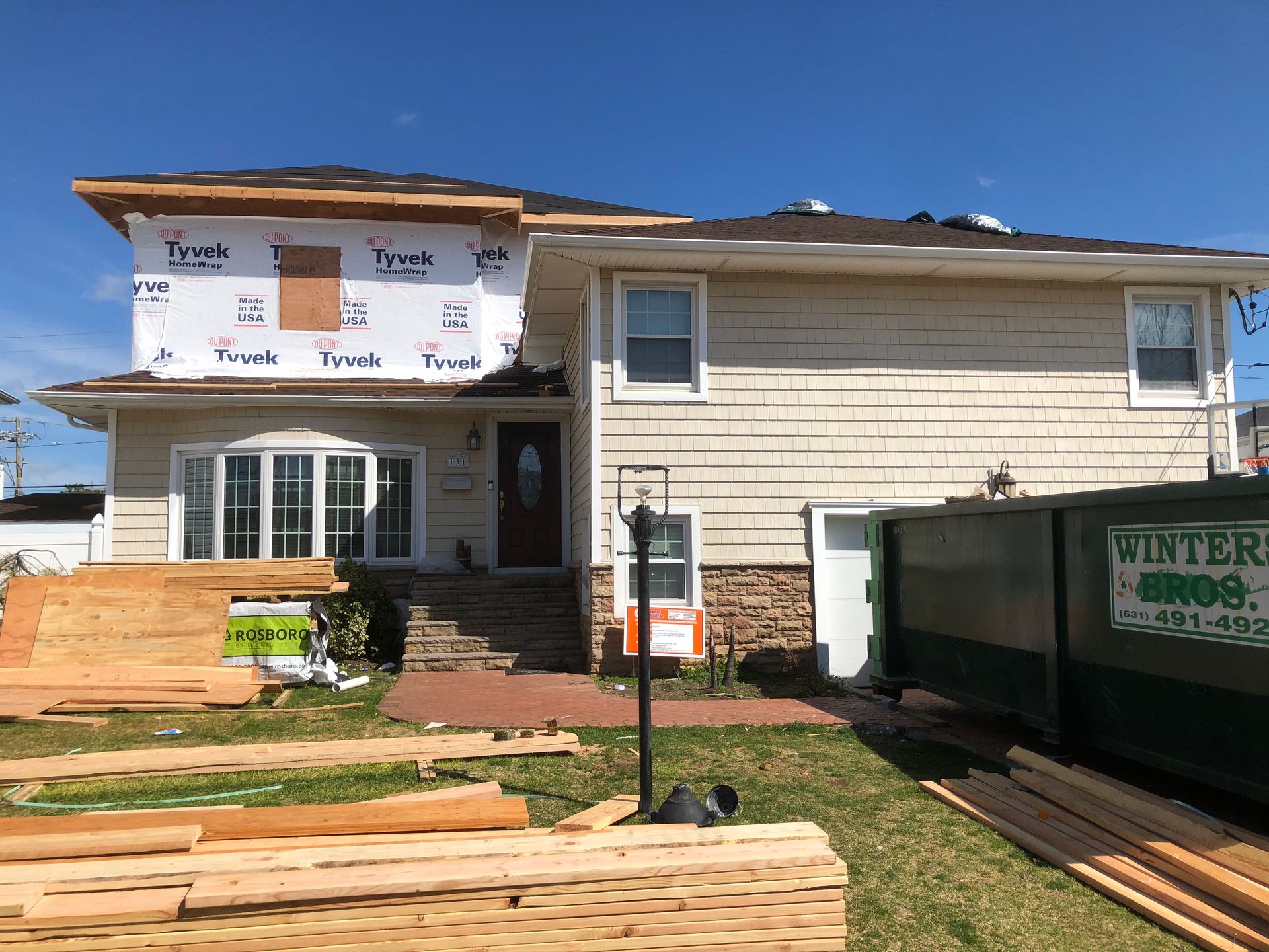A house under construction with a dumpster in front of it.