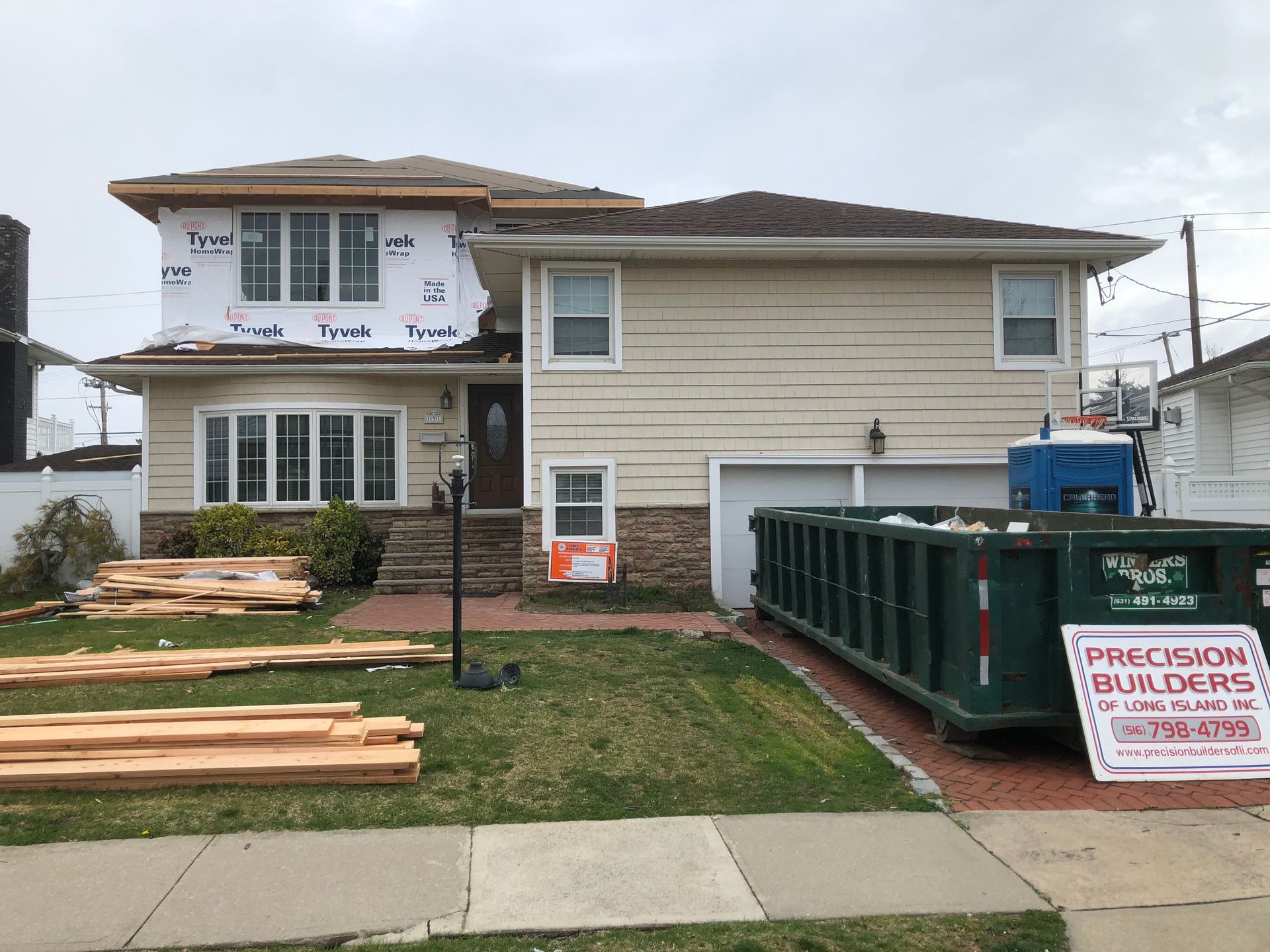 A house under construction with a dumpster in front of it.