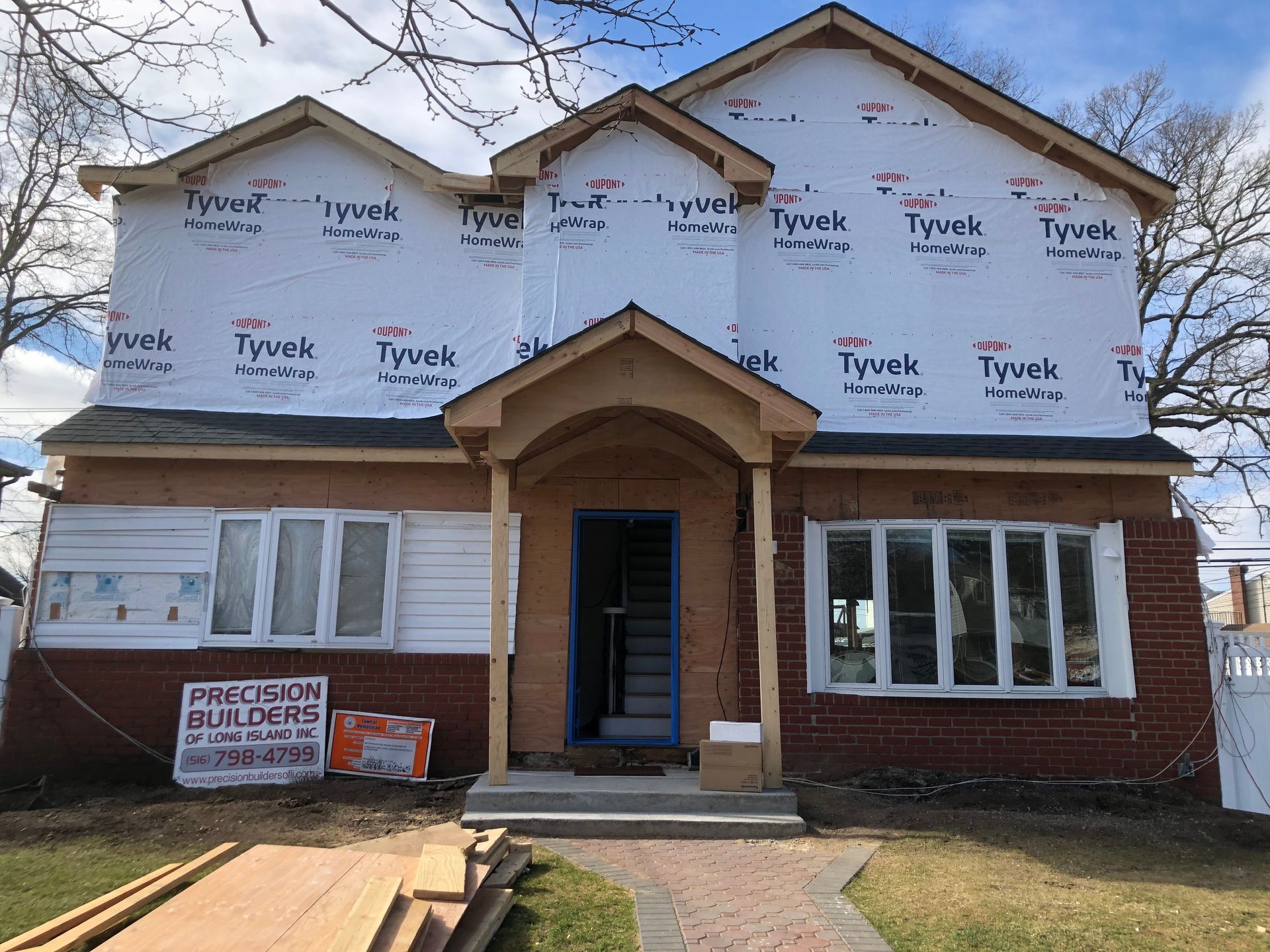 A house is being remodeled with a sign in front of it that says precision builders.