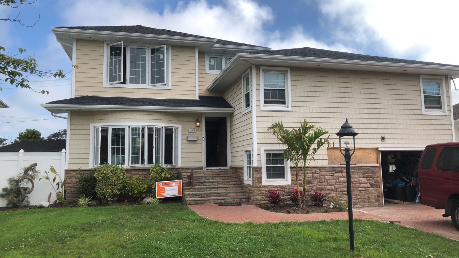A large house with a red van parked in front of it.