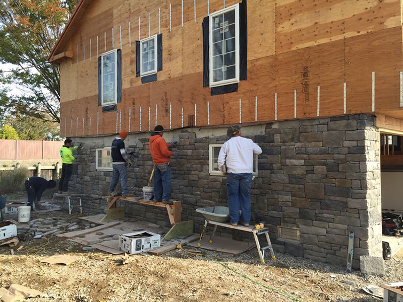 A group of men are working on the side of a house.
