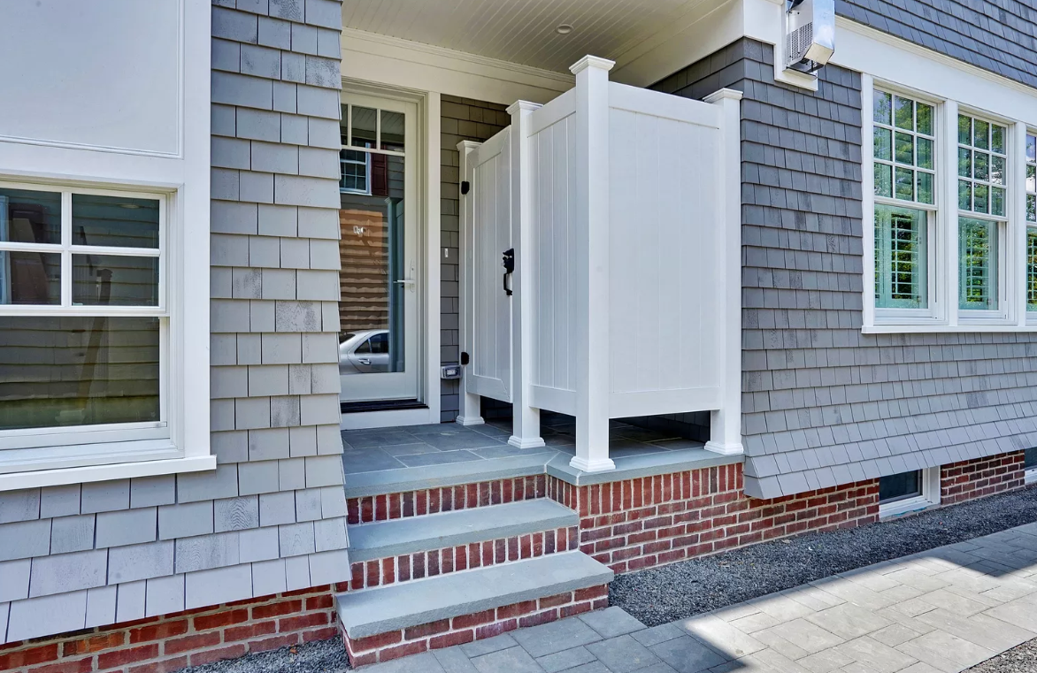 The front door of a house with a white fence and stairs leading up to it.