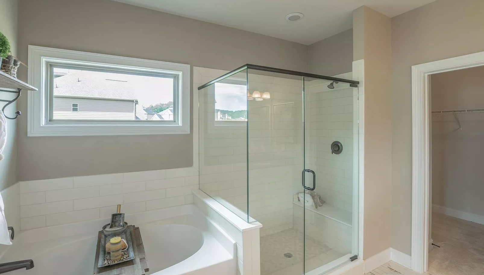 A bathroom with a tub , shower , and window.