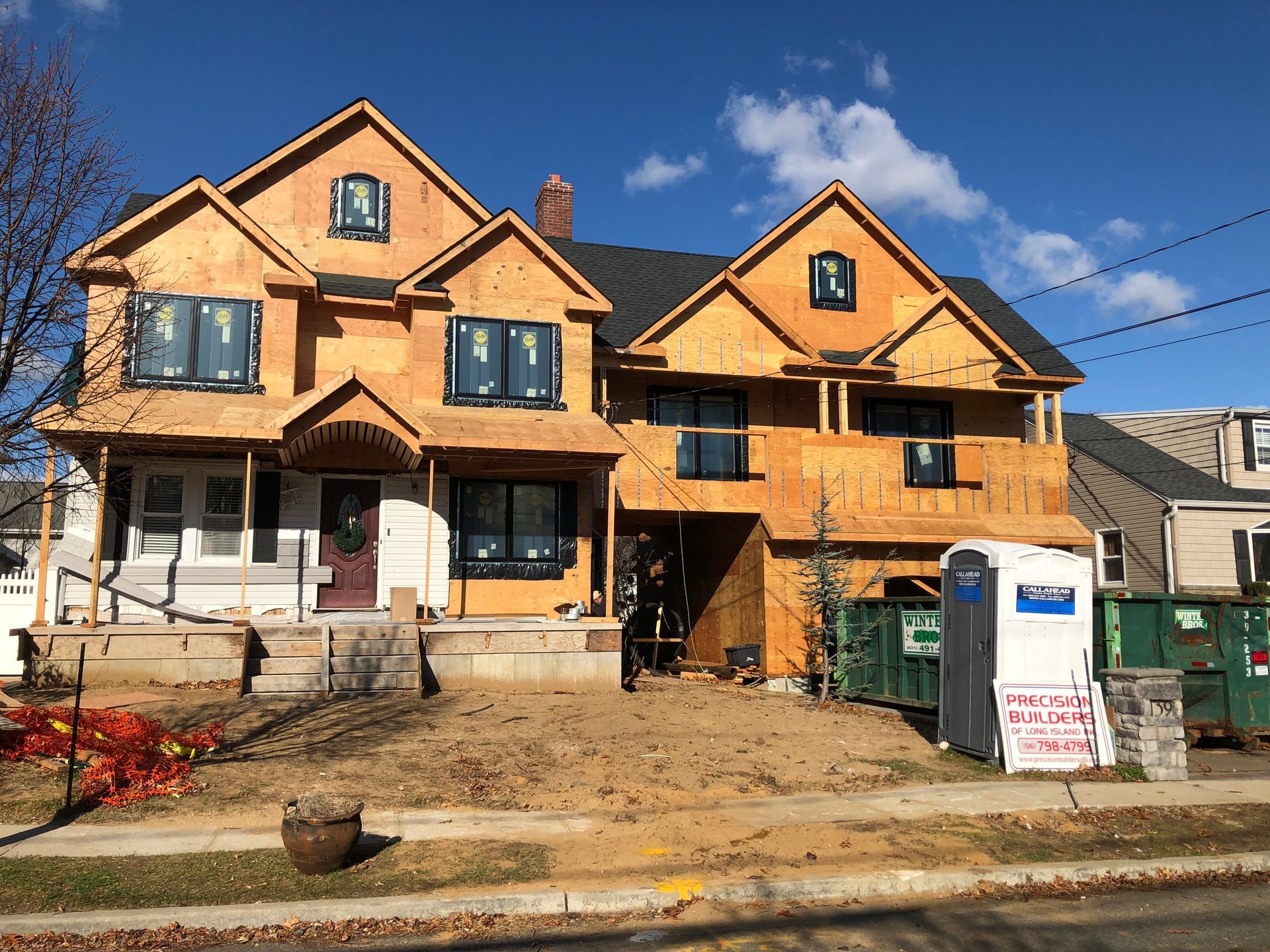 Two houses are being built next to each other on a sunny day.