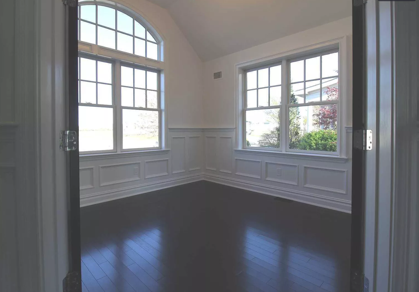 An empty room with a vaulted ceiling and lots of windows