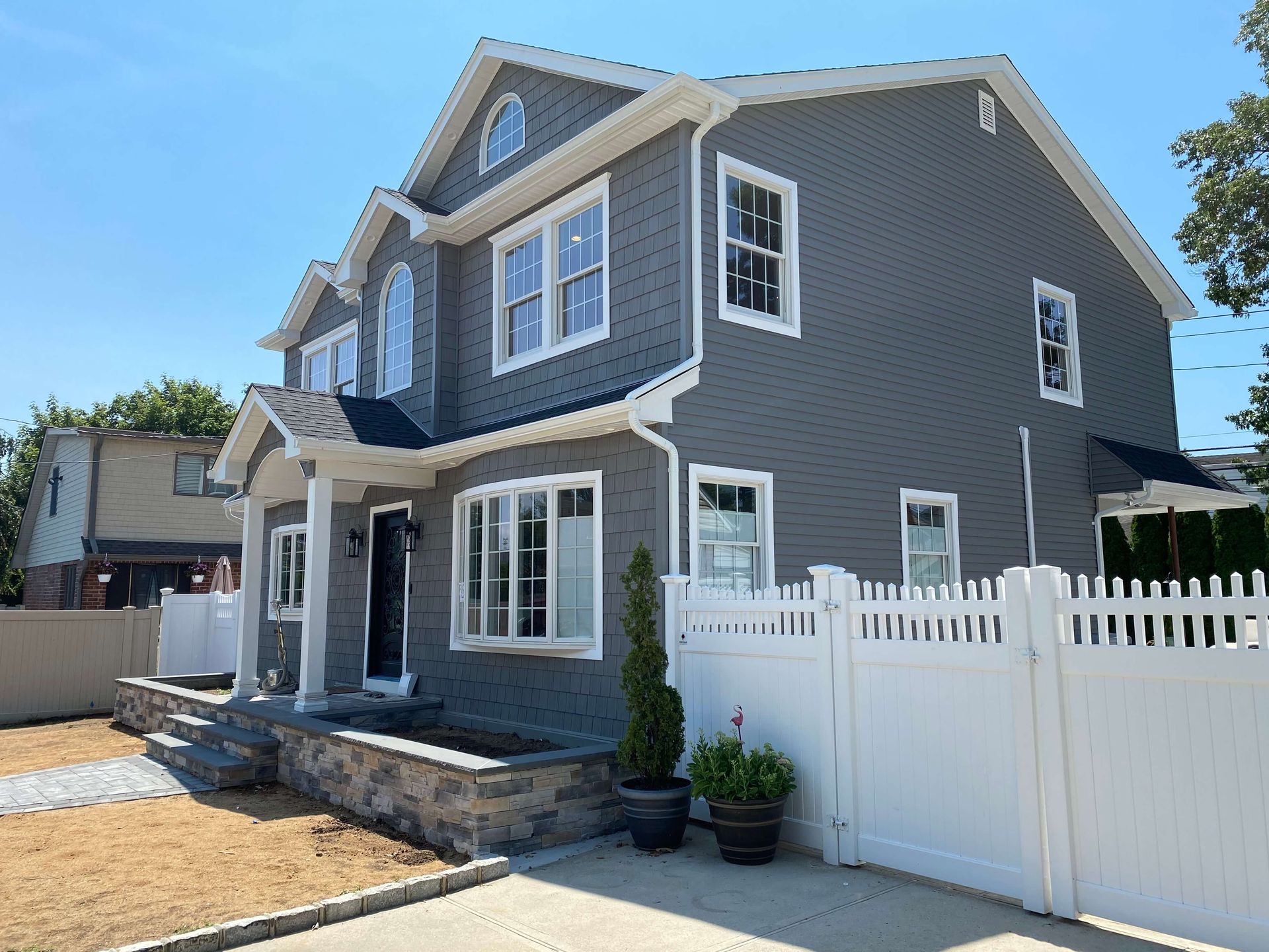 A large gray house with a white picket fence in front of it