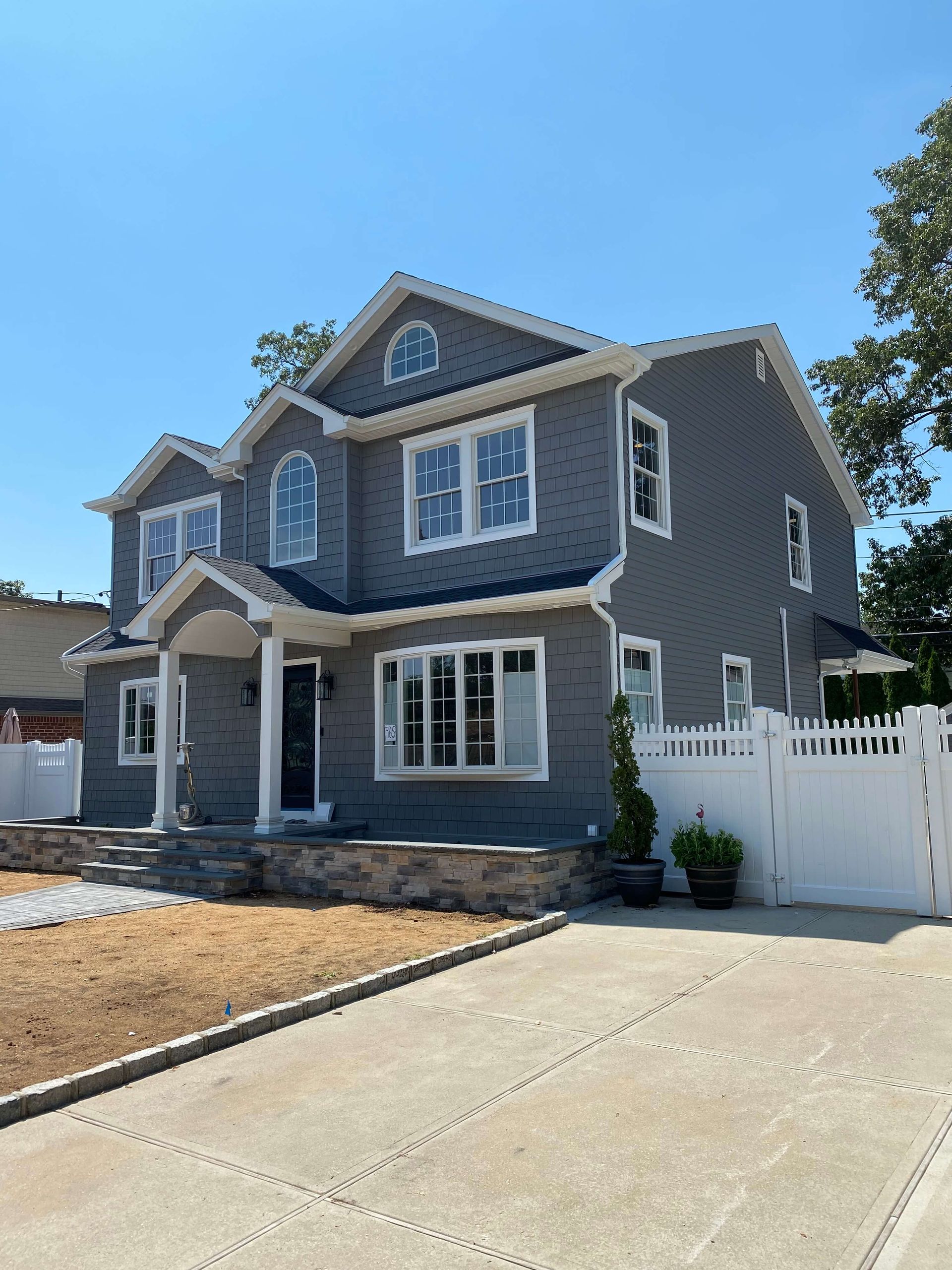 A large gray house with a white fence in front of it.