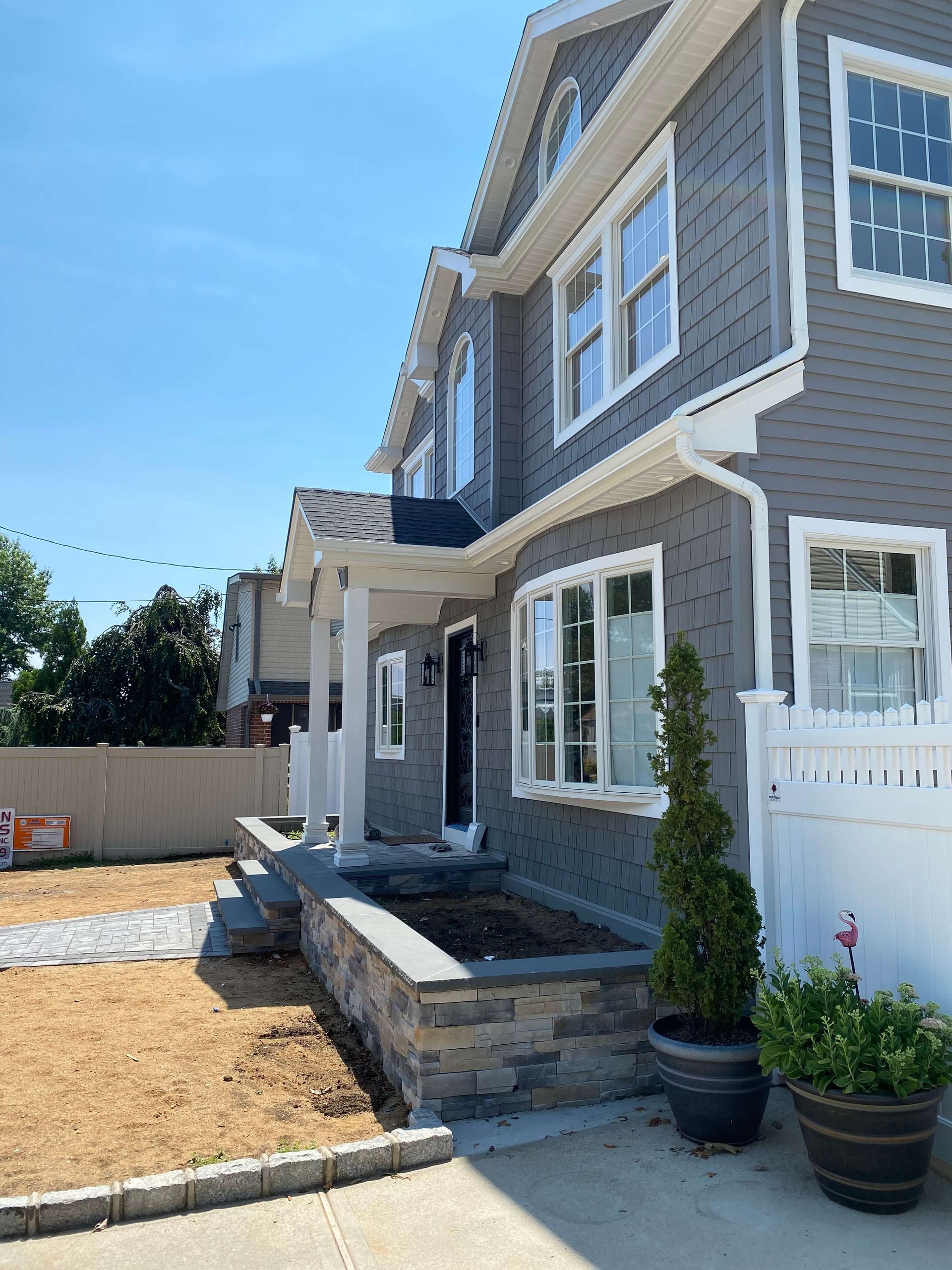 A large gray house with a white fence and a lot of windows