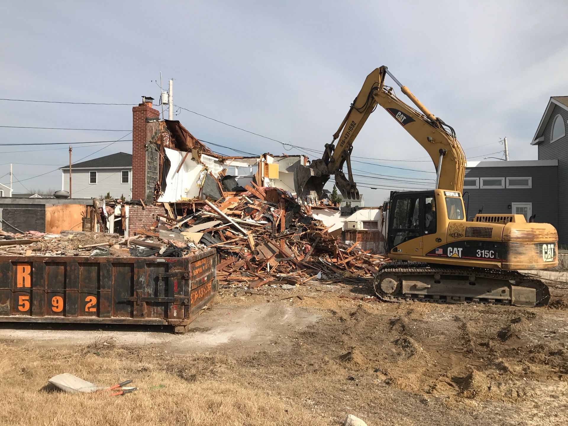 A large yellow excavator is demolishing a house.