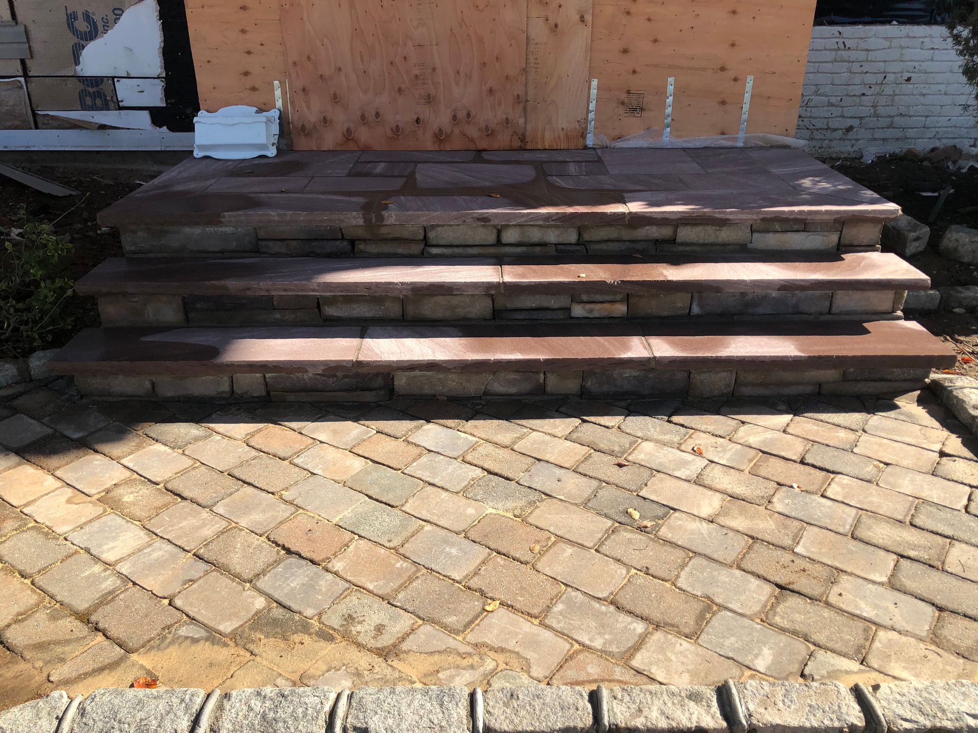 A set of stairs made of bricks are sitting on top of a brick patio.