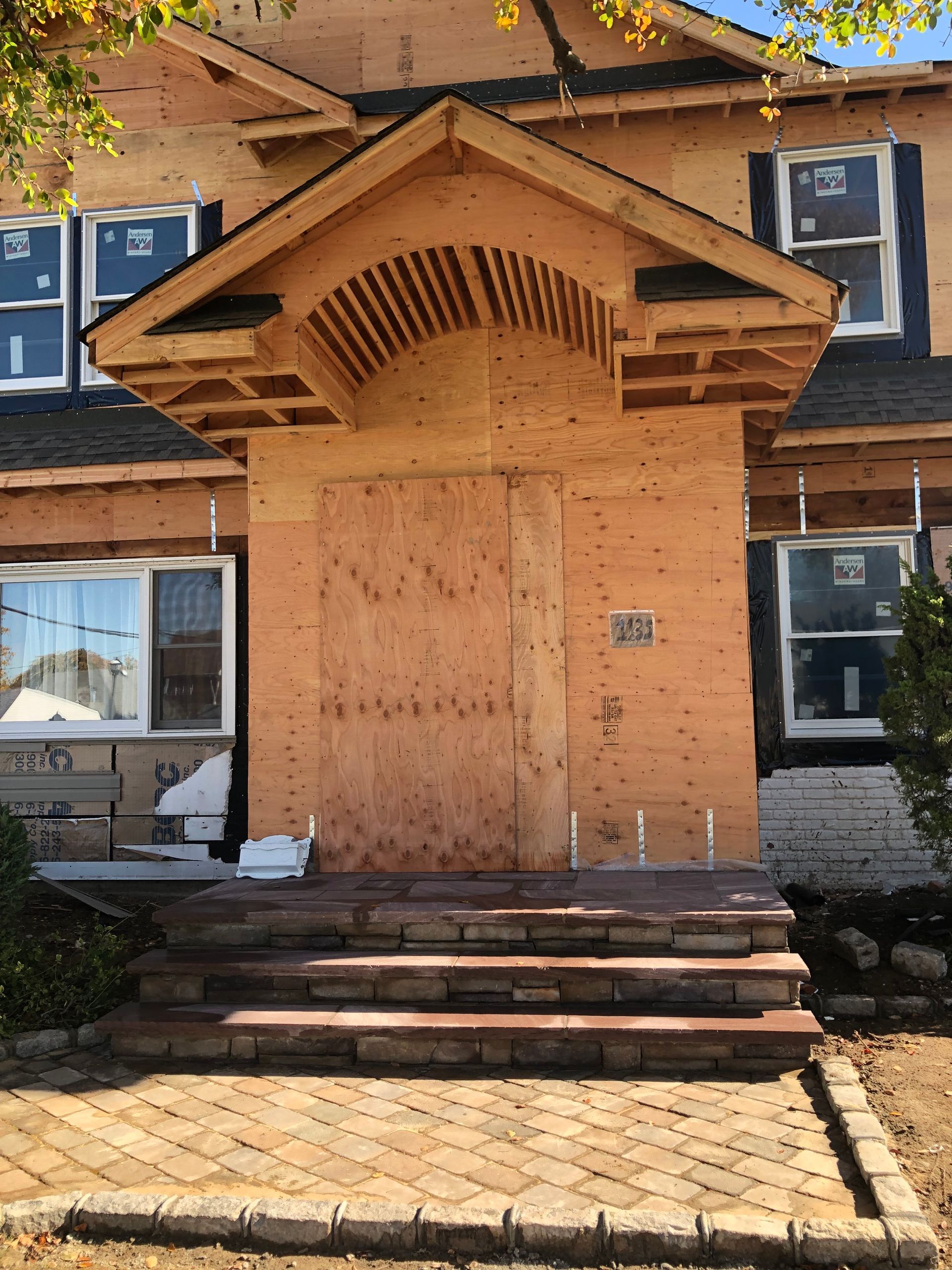 The front door of a house is boarded up with plywood.