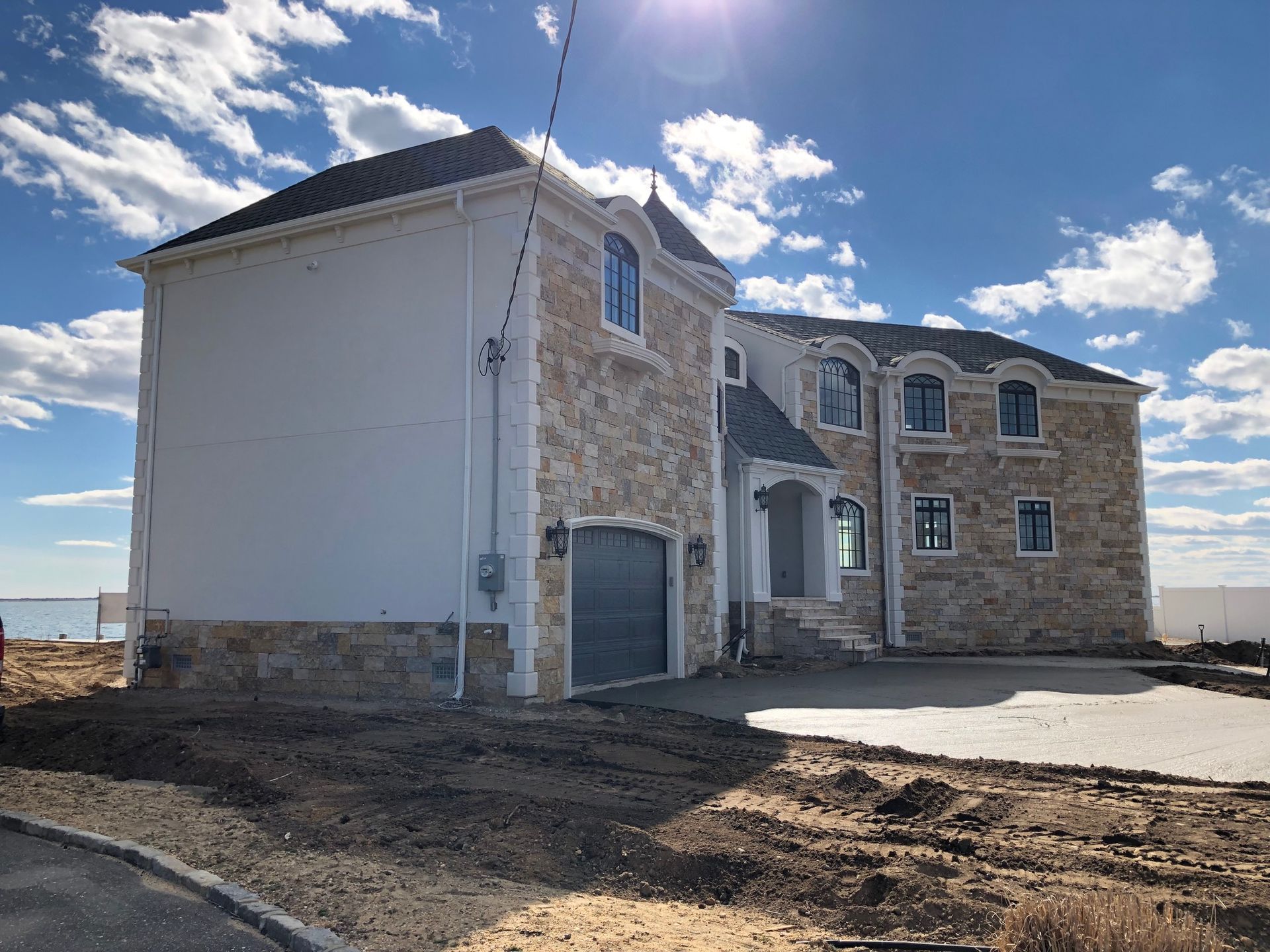 A large house with a garage is sitting on top of a dirt hill.