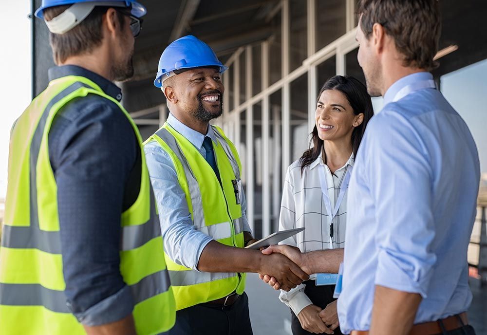 A group of construction workers are shaking hands with a businessman.