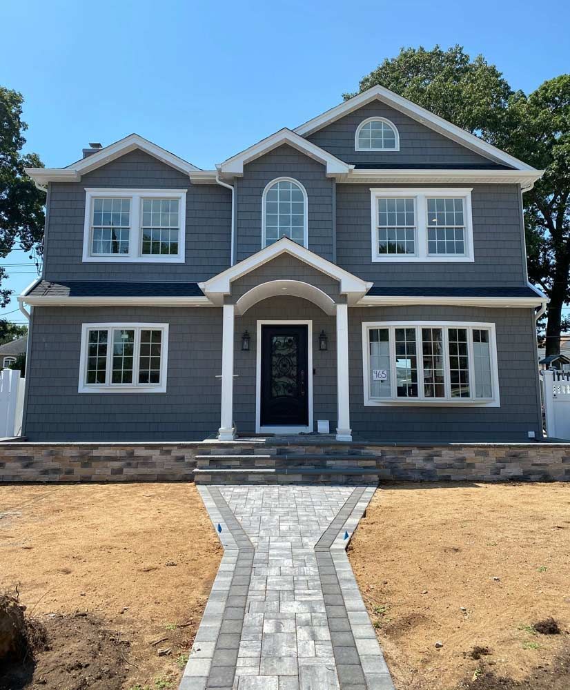 A large gray house with a brick walkway leading to it