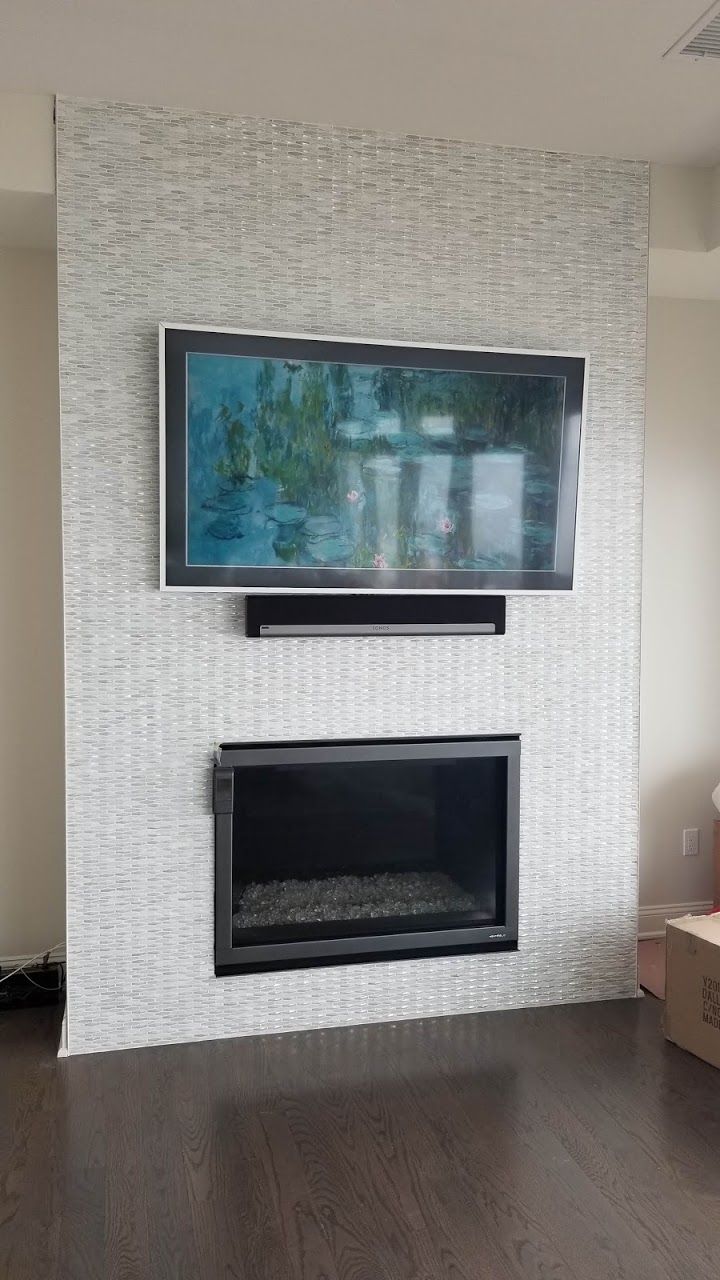 A living room with a fireplace and a flat screen tv mounted on the wall.