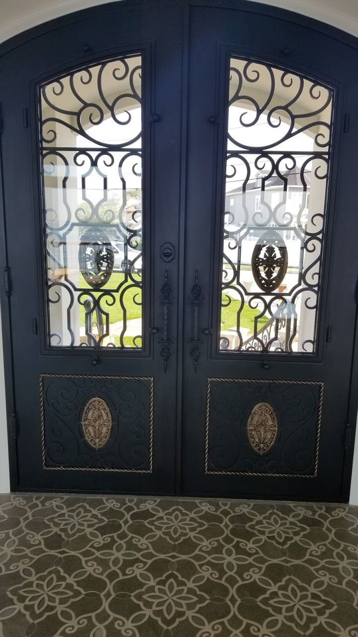 A pair of wrought iron doors with a floral pattern on the floor.