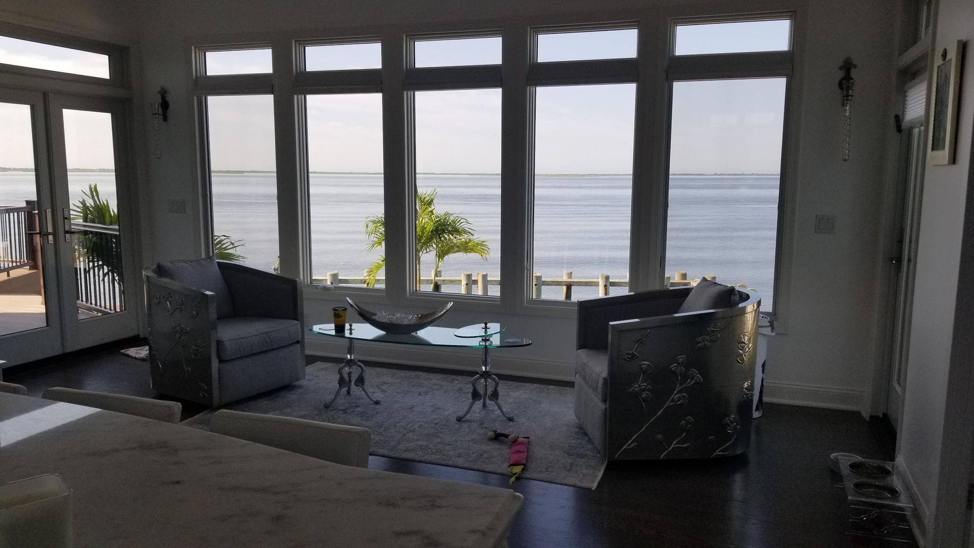 A living room with a lot of windows overlooking the ocean.