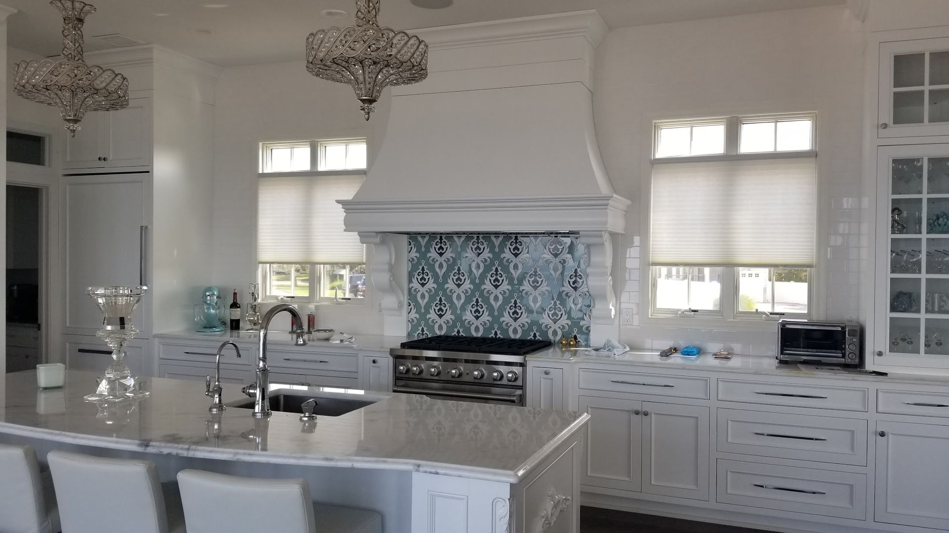A kitchen with white cabinets , a stove , a sink , and a large island.