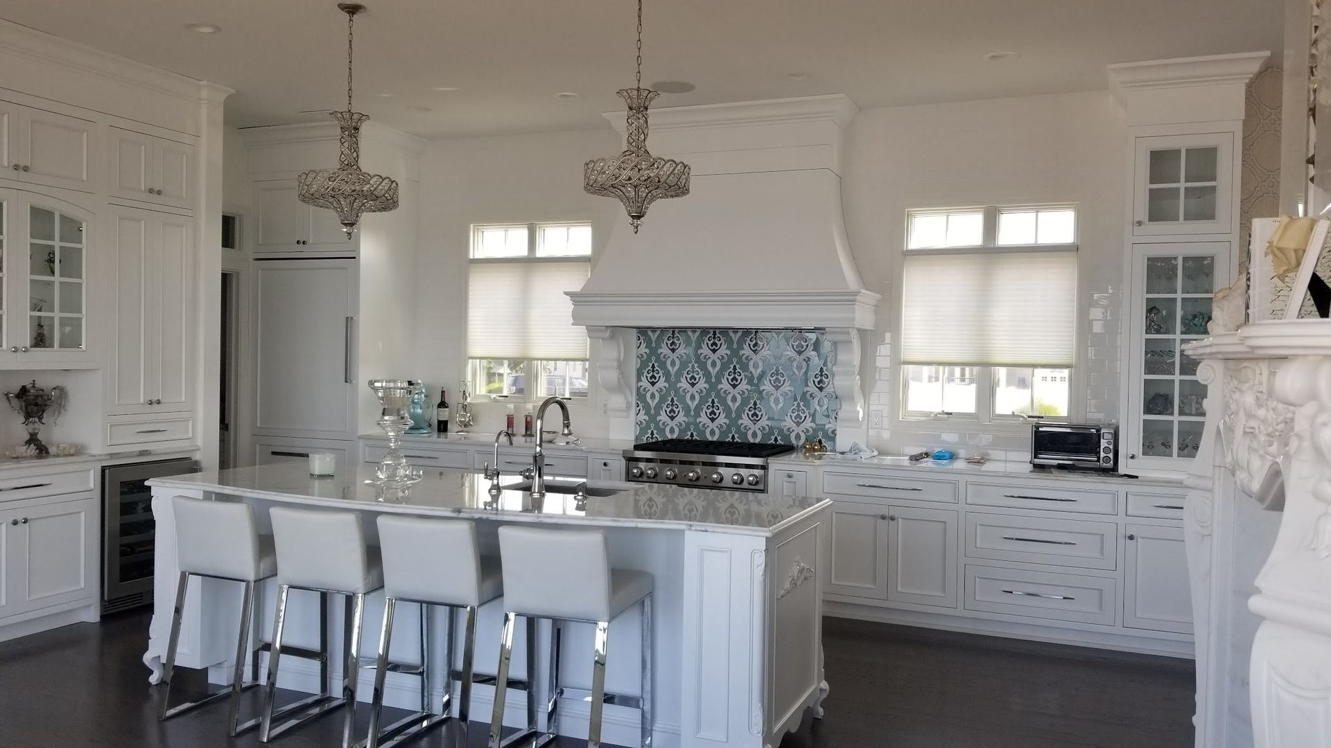 A large kitchen with white cabinets and stools and a large island.