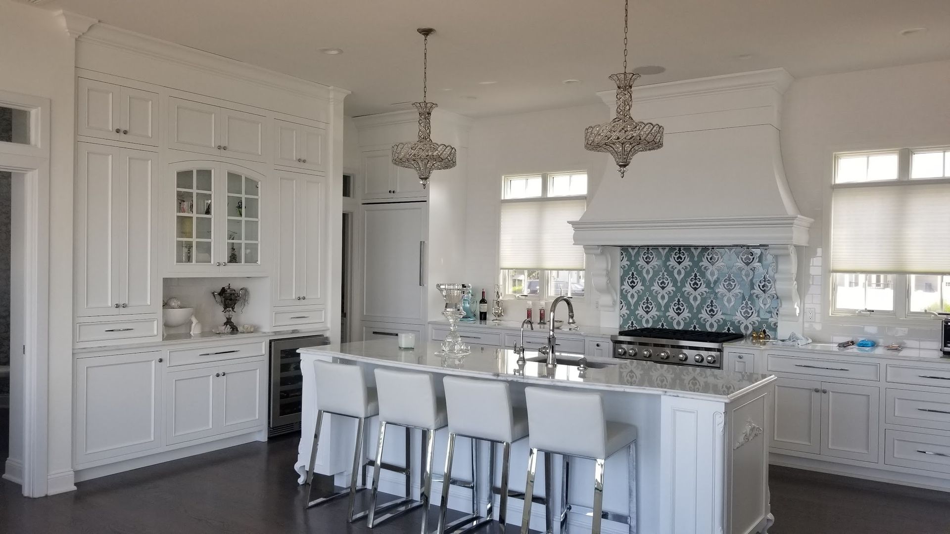 A large kitchen with white cabinets and stools and a large island.